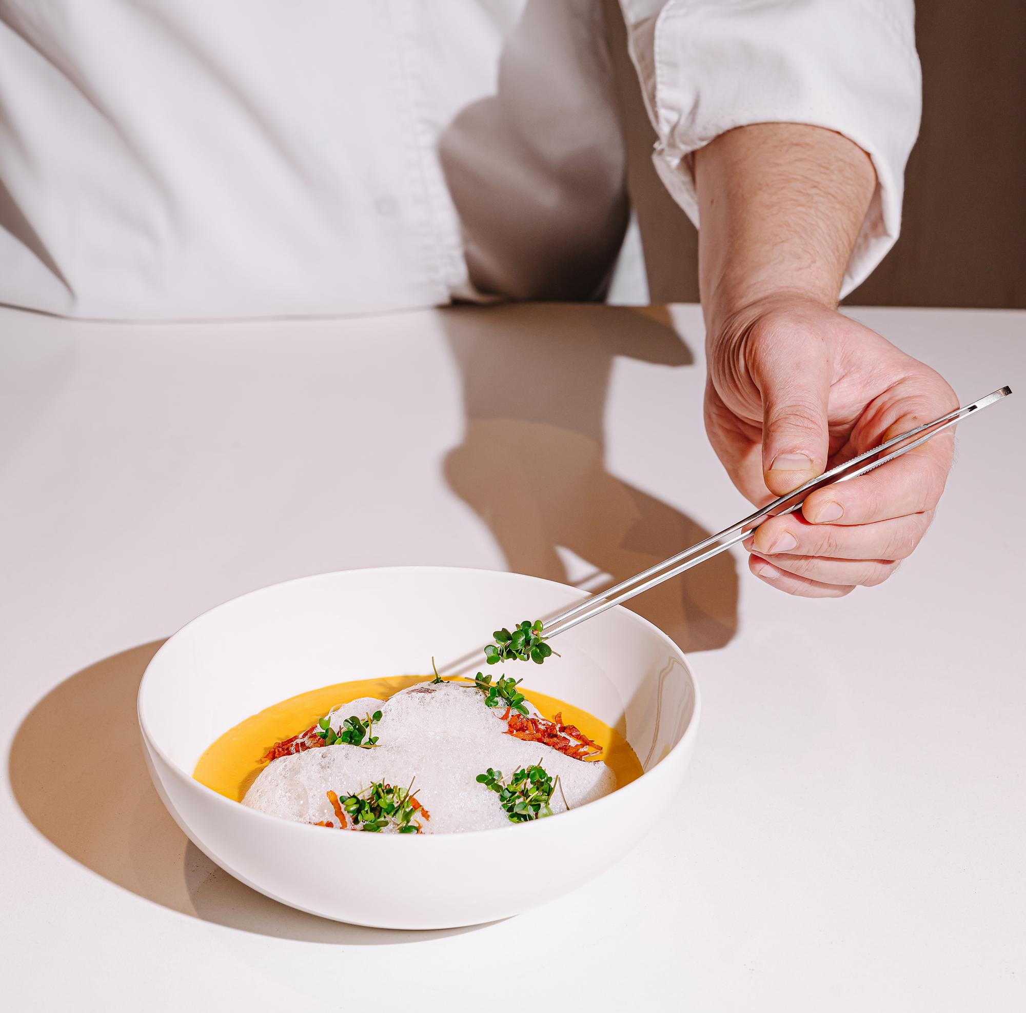 Chef hands garnishing a small bowl