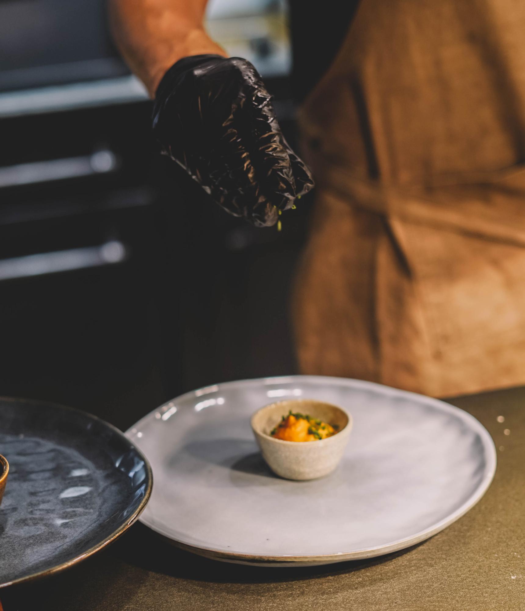 Chef preparing a plated modern dish on wooden table